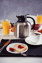 Breakfast with sandwich, coffee, juice and jam on white table