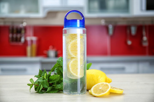 Bottle With Lemon-infused Water And Mint On Kitchen Table