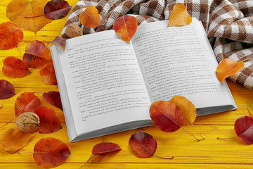 Naklejka na ściany i meble Book with autumn leaves and warm checkered plaid on yellow wooden background