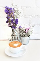 Hot coffee with heart make up on milk cream and smart phone on white table background.