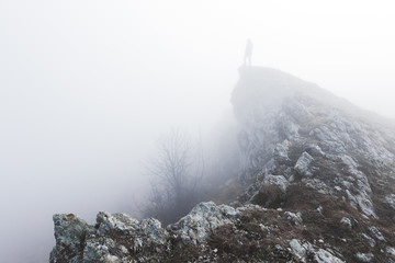 Man standing alone in the fog in mountains