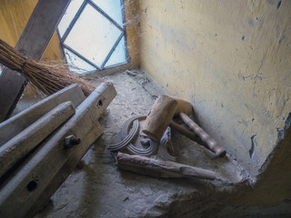Picture of an old self-made wooden hammer, mallet, close up. Two wooden hammers laying on the yellow windowstool near the broom and wooden planks. A spider web in the coner of the window.