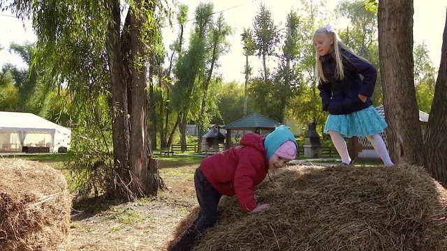 Two little girls playing in spring outdoor on a haystack