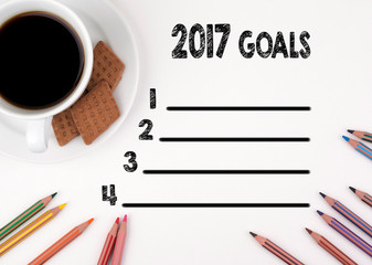 2017 goals list. White desk with a pencil and a cup of coffee.