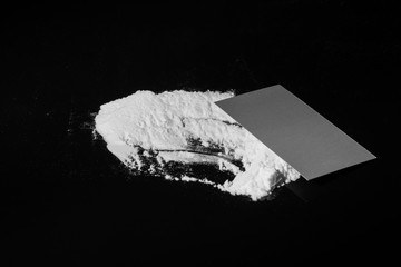 white drug dust with credit card on black background, monochrome