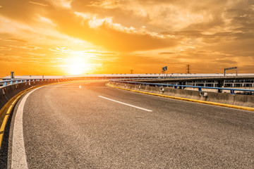Fototapeta premium Asphalt road and woods at sunset