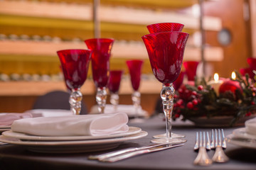 round table decorated with red wine glasses, a black tablecloth and italian dishes