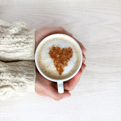 favorite coffee with mood/ heart symbol decorate frothy cappuccino in a white cup in his hand 