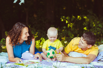 The mother,father and  son lie on the carpet in park