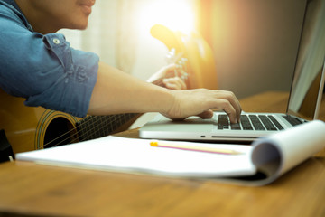 Man practicing play the guitar with laptop