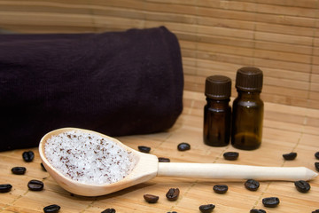 Spa concept.Coffee scrub, coffee beans, towel, aroma oil, candle on straw mat  background