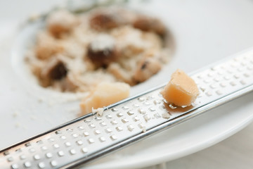 Grating parmesan cheese for italian cuisine dish, wild mushroom risotto