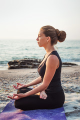 Fototapeta na wymiar young caucasian female practicing yoga on the beach