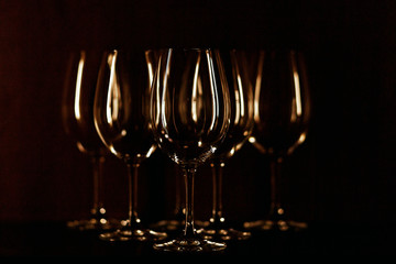 Wineglasses illuminated with warm light stand on black backgroun