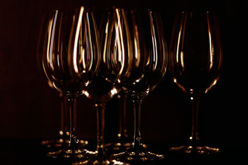 Crystal wineglasses illuminated with warm light stand on black b