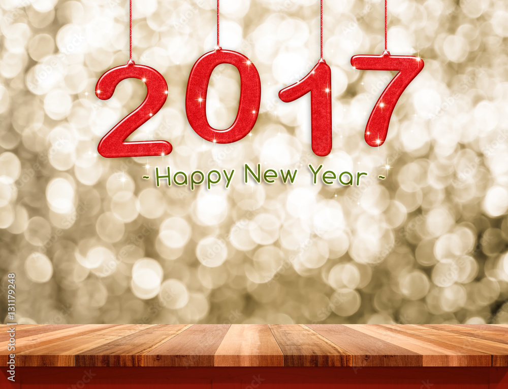 Aufkleber 2017 new year hanging over plain wood table top with gold sparkl