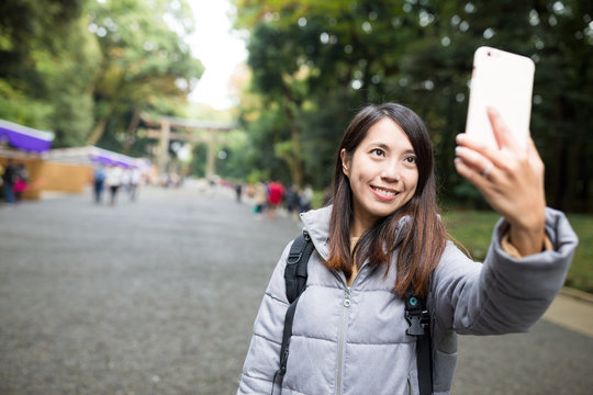 Woman taking selfie by mobile phone at Japanese temple