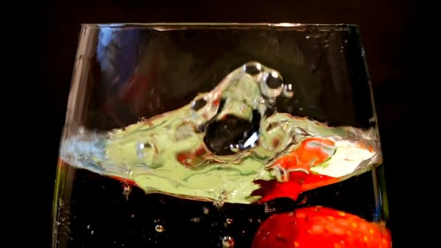 물컵에 빨강 딸기를 낙하하는 장면을 슬로우 모션으로 담다.