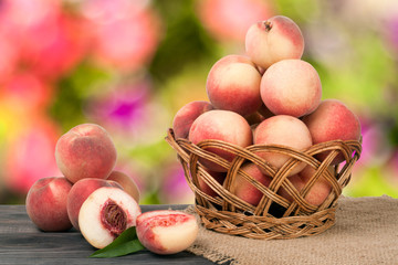 peaches in a wicker basket on wooden table with blurred background