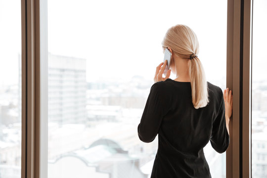 Back View Image Of Young Woman Worker Talking By Phone.