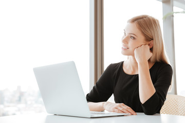 Thoughtful young lady worker using laptop computer