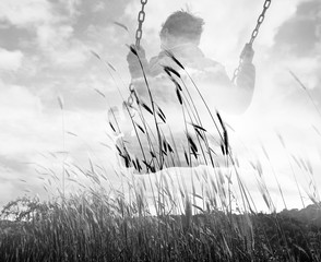 Monochrome double exposure of kid on swing and wheat field
