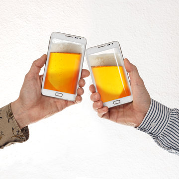 Two male hands in shirts hold smart phones with beer against white background
