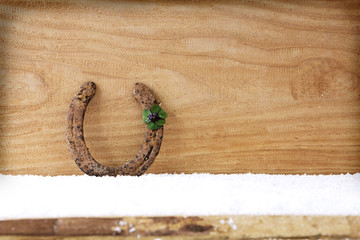 Horseshoe four leaf clover on wood.