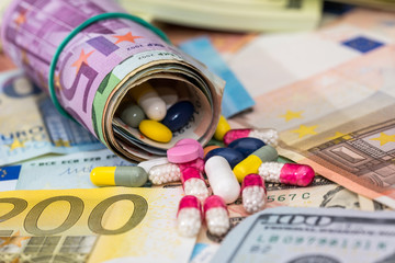 macro pills and tablets on euro and dollar banknotes for background.
