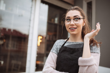 Surprised young woman confectioner standing near cafe