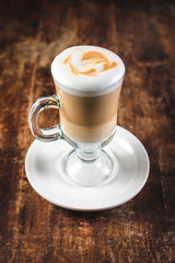 latte in a tall glass beaker on  wooden table