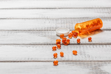 Omega 3 fish oil capsule with pill bottle on white wooden table. Health care 