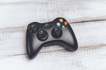 Wireless black gamepad or game controller for console gaming on white wood table