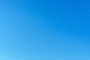 water drops on glass with blue sky background