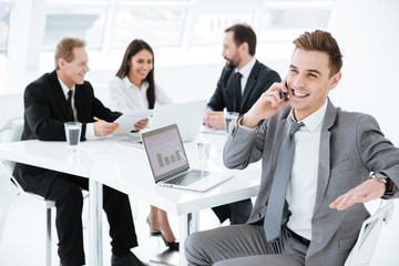 Portrait of young business man by the table with colleagues