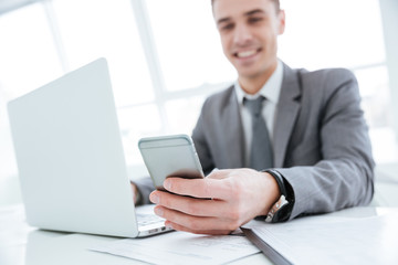 Business man sitting by the table with laptop and phone