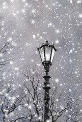 Fototapeta na wymiar Christmas background. Vintage street lamp with light among shine snow. Christmas landscape