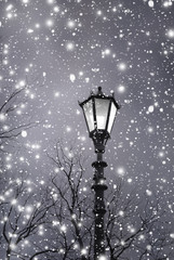 Fototapeta na wymiar Christmas background. Vintage street lamp with light among shine snow. Christmas landscape 