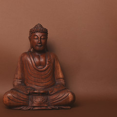 Wooden buddha statue against brown backgound