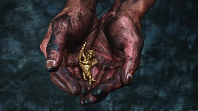 4k Technical Composition of Dirty Mechanic Hands Holding Angel