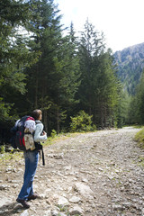 Fototapeta na wymiar femme avec un sac à dos qui fait de la randonnée dans la forêt en montagne
