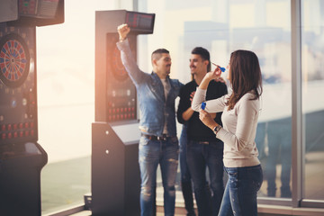 Young friends playing darts in a club