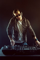 Fototapeta na wymiar DJ mixing music on mixer on dark background