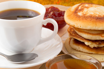 Pancakes on a plate and cup of coffee close-up