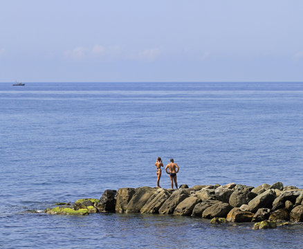 people are resting on a stone pier in Khosta, Russia