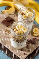 Granola. Granola with yogurt, chocolate and banana on blue concr