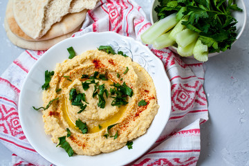 Home classic hummus with celery, pitoy.Vid top on gray concrete background. Vegan Food Concept.