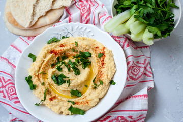 Home classic hummus with celery, pita. View top on gray concrete background. Vegan Food Concept.
