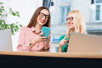 Young business women working with laptops sitting on the window background at the cafe