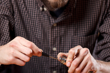 Vape. One man in a vape bar (shop) is repairing e-cigarette.